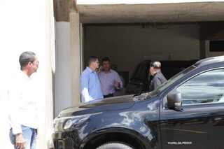 Rodeado de seguranças, Eduardo Riedel chega ao telefone no estacionamento da Governadoria na tarde desta segunda-feira (6). (Foto: Kísie Ainoã)