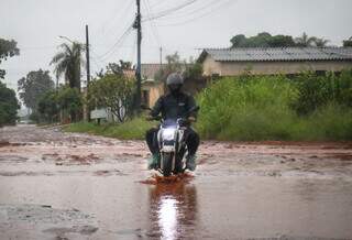 Com sacolinhas nos pés, motocilista enfreta enxurrada no Nova Lima. (Foto: Henrique Kawaminami)