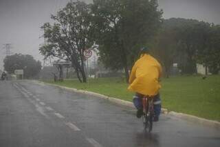 Ciclista, vestindo capa de chuva, transita pela Avenida Ministro João Arinos, em Campo Grande. (Foto: Henrique Kawaminami)