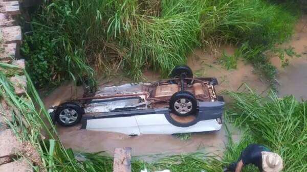 Após forte chuva motorista tenta desviar de poça, carro derrapa e cai em córrego