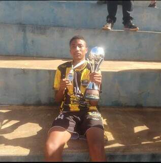 Júlio Cesar segurando troféu e medalha que conquistou em campeonato de futebol. (Foto: Reprodução/Facebook)