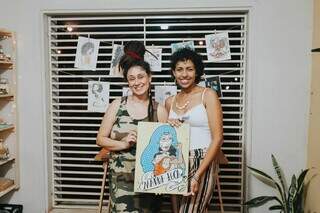 (À esquerda) Patrícia Rodrigues e Erika Pedraza com o quadro &#39;Madre Loca&#39;. (Foto: @olhaosframes)