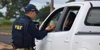Policial aplica teste de bafômetro em motorista, durante fiscalização em rodovia. (Foto/Divulgação)