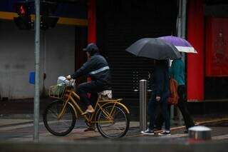 Trabalhador de bicicleta tira sapato e coloca chinelo para não molhar na chuva (Foto: Henrique Kawaminami)