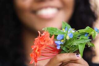 Adolescente segura flores e sorri em quintal (Foto: Henrique Kawaminami)