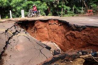 Motociclista passa em calçada oca, próximo de cratera na Rua Rivaldi Albert (Foto: Henrique Kawaminami)