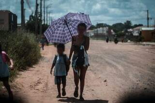 Mulher caminha com criança em rua da Favela da Homex, no Jardim Centro Oeste, em Campo Grande (Foto: Marcos Maluf)