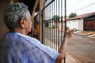 Do portão, ela aponta casas dos vizinhos que saíram do bairro. (Foto: Henrique Kawaminami)