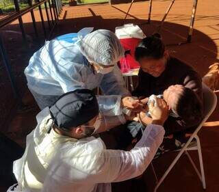 Profissionais do HU de Dourados aplicam vacina em criança indígena durante vista a aldeias (Foto: Divulgação)