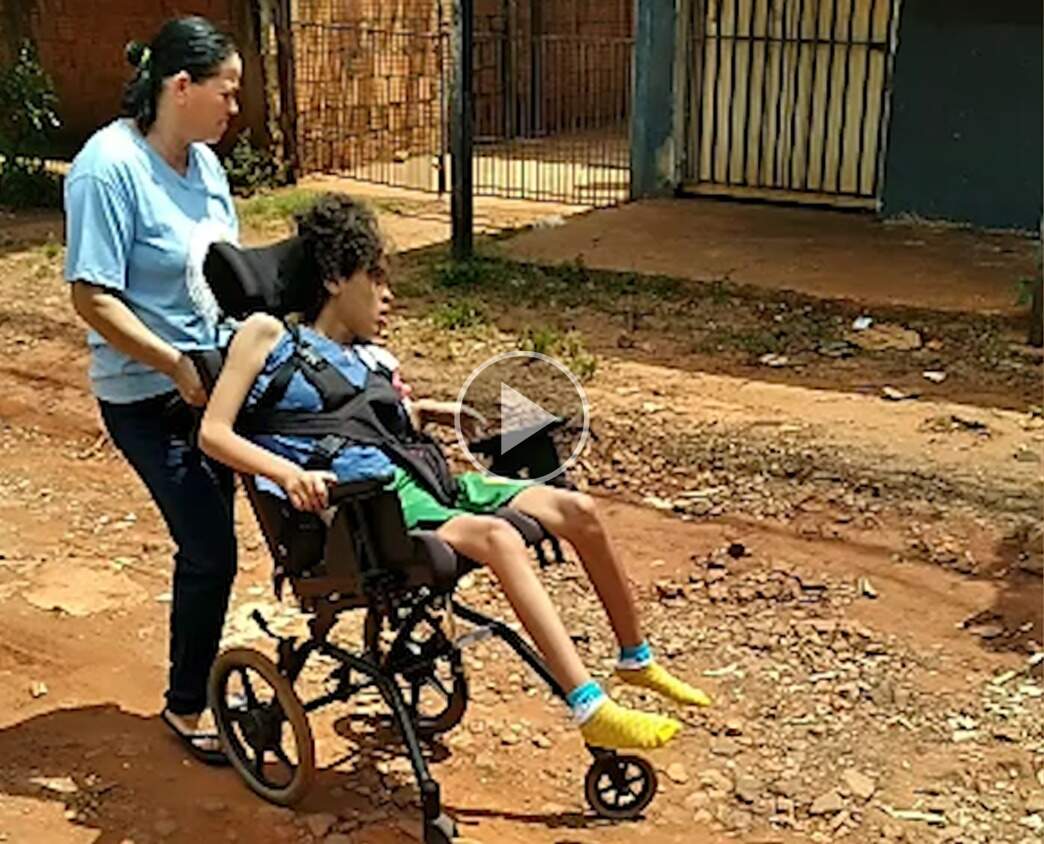 Em rua sem asfalto, conserto de cadeira de rodas vira rotina para moradora