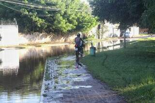 Motociclista usa calçada para escapar de água da Lagoa Itatiaia (Foto: Paulo Francis)