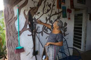 Moradora mostra pintura de àrvore que fez na parede da varanda. (Foto: Paulo Francis)