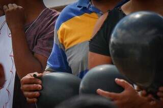 Filho de Cauby segura balão preto em frente ao Cemitério Santo Antônio nesta sexta-feira (14). (Foto: Henrique Kawaminami)