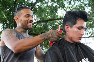 Bruno corta o cabelo de Marcos Txekewe em local improvisado na Avenida Afonso Pena (Foto: Juliano Almeida)