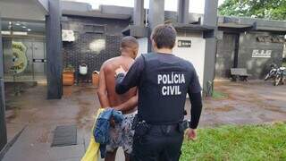 Policial conduz um dos presos em operação deflagrada hoje em Dourados (Foto: Adilson Domingos)