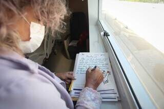 Apoiada na janela, a idealizadora do projeto redige o poema. (Foto: Marcos Maluf)