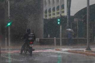 Motociclista e pedestre lidam com a chuva em trecho da Avenida Afonso Pena, no Centro da Capital. (Fotos: Henrique Kawaminami)