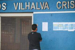 Pai de aluno lendo aviso sobre paralisação de professores, na Escola Municipal Carlos Vilhalva Cristaldo (Foto: Henrique Kawaminami)