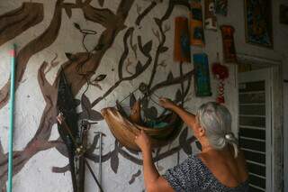 Moradora arrumando alguns quadros em sua residência (Foto: Paulo Francis)