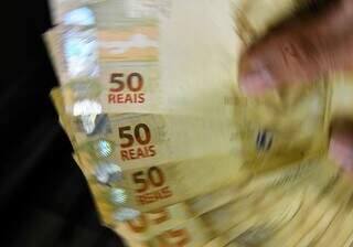 Mão mostra várias notas de R$ 50,00. (Foto: Agência Brasil)