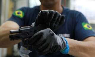 Policial manipula uma pistola. (Foto: Diego Vara/Agência Brasil)