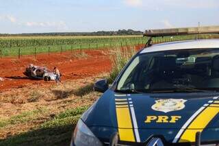 Viatura da PRF no local do acidente. Ao fundo, carro aparece destruído. (Foto: Henrique Kawaminami)