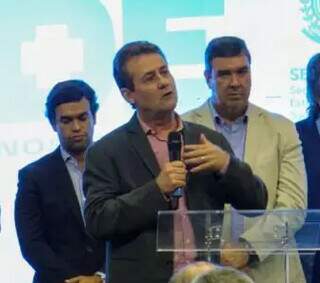 Secretário de saúde discursa ao lado do governador Eduardo Riedel (à direita) e do deputado Beto Pereira (à esquerda)