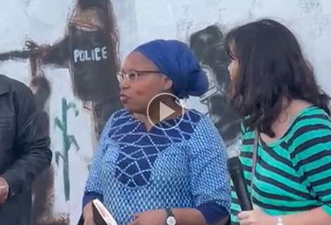 Em frente à pintura encenando ataque da PM, conselheira fala a indígenas