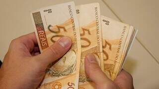 Homem conta cédulas de dinheiro. (Foto: Arquivo/Campo Grande News)