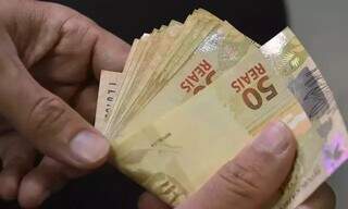 Pessoa conta cédulas de dinheiro. (Foto: Agência Brasil/Reprodução)