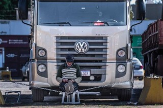 Caminhoneiro José Antônio sentado em um banco, mexendo no celular (Foto: Marcos Maluf)