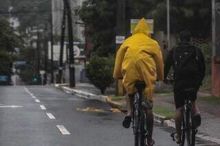 Ciclista com capa de chuva para não se molhar na manhã deste domingo, na Avenida Afonso Pena (Foto: Marcos Maluf)