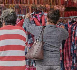 Aposentada Bernarda Morais olhando roupas, em loja na Rua 14 de Julho (Foto: Marcos Maluf)