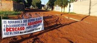 Cartaz próximo de um lamaçal provocado pelas obras (Foto: Juliano Almeida)