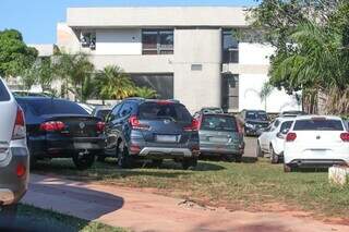 Carros estacionados na grama em frente à secretaria. (Foto: Marcos Maluf)