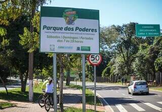 Placa mostra dias de interdição parcial e ao fundo carro passando na via aberta e ciclistas na ciclovia (Foto: Henrique Kawaminami)