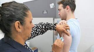 Funcionária aplica dose de vacina em rapaz (Foto: PMCG)