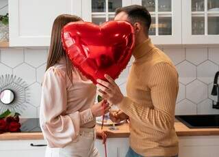 Casal segurando um balão em formato de coração. (Foto: Freepik)