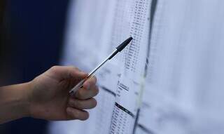 Estudante verifica lista de aprovados em vestibular com uma caneta preta. (Foto: Marcelo Casal Jr./Agência Brasil)
