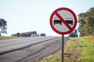 Apesar da falta de faixas na pista, placa indicando a proibição de ultrapassagem está fixada a alguns metros do local do acidente (Foto: Henrique Kawaminami)