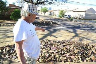 Júlio César aponta punhado de folhas acumuladas na Na Rua da Amapolas no bairro Piratininga (Foto: Alex Machado)