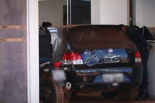 Policiais vistoriando Fiat Palio e motocicleta encontrados na casa. (Foto: Henrique Kawaminami)