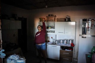 Moradora mostra casa sem luz, desde a operação. (Foto: Henrique Kawaminami)