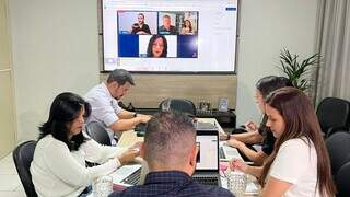 Reunião entre especialistas em educação da Semed (na mesa) e do Canadá (na televisão) Foto: Divulgação/Prefeitura de Campo Grande)