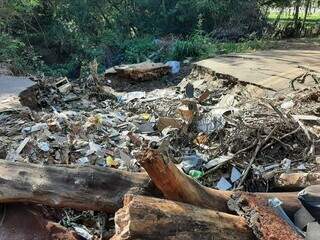 Lixo e entulho descartados na cratera aberta há mais de quatro meses na via, em decorrência da chuva (Foto: Idaicy Solano)