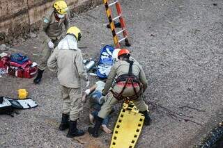 Mulher caída na parte de concreto do córrego e sendo socorrida pelo Corpo de Bombeiros. (Foto: Henrique Kawaminami)