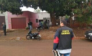 Casa onde menino foi morto e ao fundo, Jéssica Ribeiro conversando com delegado (Foto: Adilson Domingos)