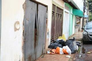 Portão que foi arrombado e lixo em frente ao imóvel. (Foto: Alex Machado)