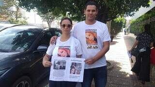 Patricia da Silva, mãe da jovem, e Luiz Henrique Azamor, padrasto da jovem, seguram cartaz pedindo por justiça. (Foto: Izabela Cavalcanti)