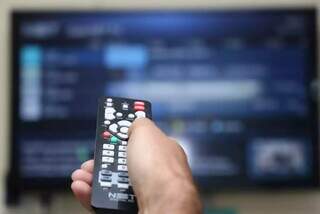 Assinante utiliza controle remoto para troca de canais em aparelho de TV. (Foto: Marcos Maluf/Arquivo)